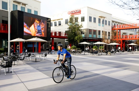 In this photo taken Tuesday Feb. 3, 2015, a man rides through his bicycle through the campus at Facebook headquarters in Menlo Park, Calif. (AP Photo/Eric Risberg)