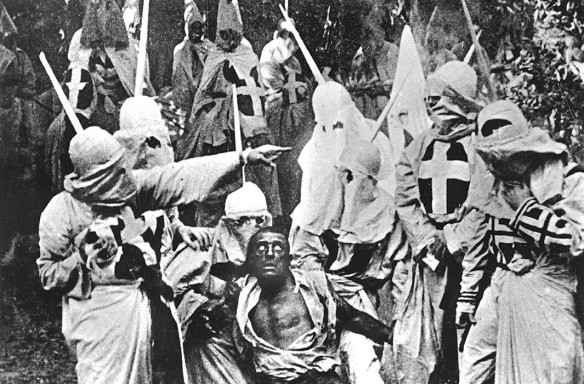 Actors costumed in the full regalia of the Ku Klux Klan chase down a white actor in blackface in a still from 'The Birth of a Nation,' the first feature-length film, directed by D. W. Griffith, California, 1914. Photo by Hulton Archive/Getty Images